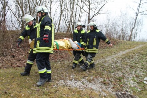 Vier Feuerwehrmänner tragen Patientin auf Trage